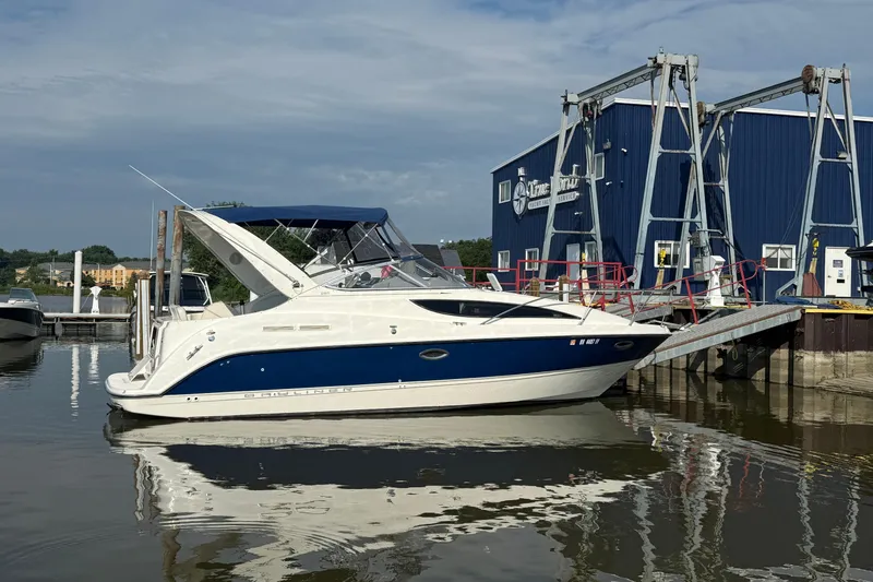 Slide: The Image of 2004 Bayliner 285 boat docked near a blue marina building. - 2