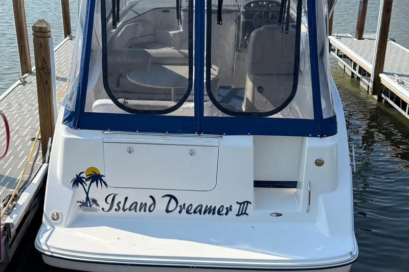 Slide: The Image of 2004 Bayliner 285 "Island Dreamer II" docked, featuring a blue canopy and tropical decal. - 22