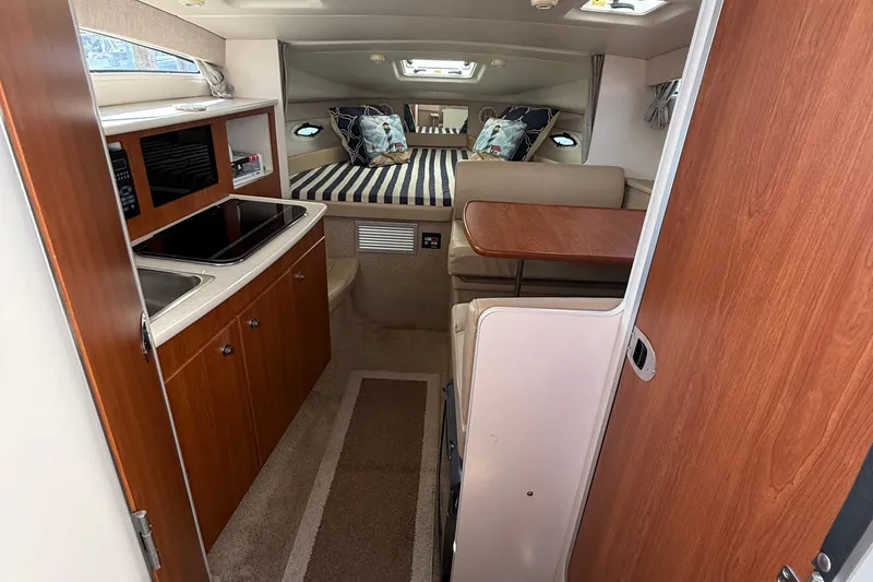 Slide: The Image of 2004 Bayliner 285 interior with kitchenette, dining area, and cozy sleeping quarters. - 9