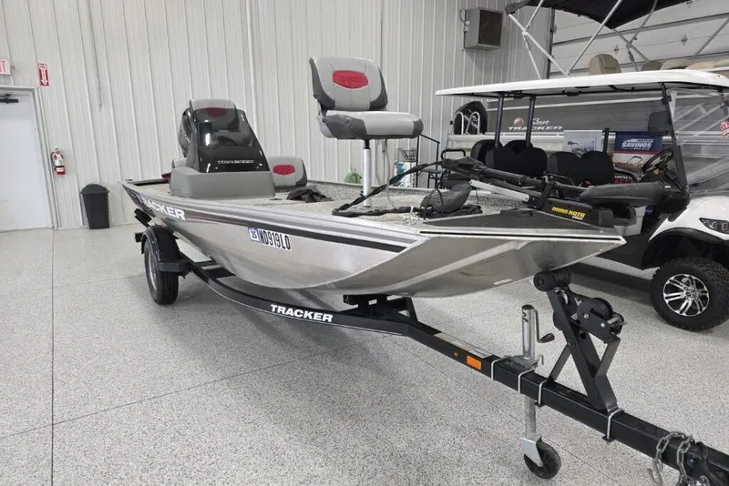 Slide: The Image of 2016 Tracker Pro 160 boat on trailer in showroom, featuring seating and motor. - 4