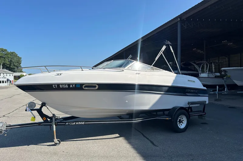 The Image of 2002 Four Winns 205 Sundowner boat on trailer in sunny marina setting. - 0