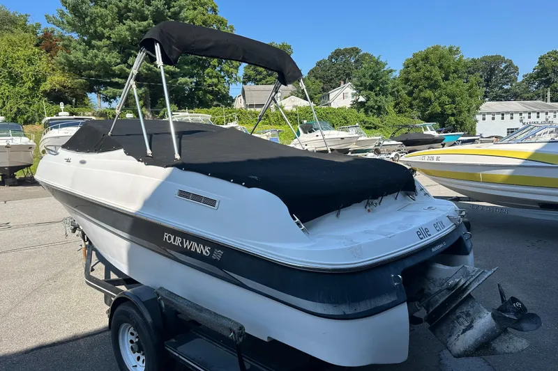 Slide: The Image of 2002 Four Winns 205 Sundowner boat on trailer, covered, in a marina setting. - 14