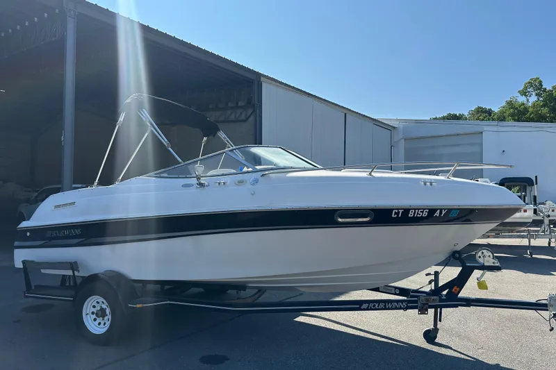 Slide: The Image of 2002 Four Winns 205 Sundowner boat on trailer, parked outside a warehouse. - 2