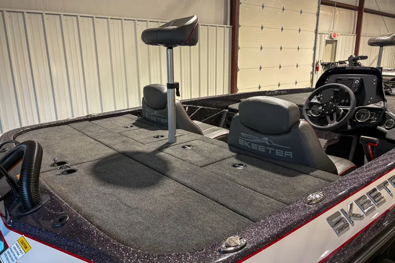 Slide: The Image of 2025 Skeeter ZX150 boat interior with steering wheel and seating in a garage setting. - 8