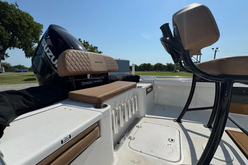 Slide: The Image of 2023 Sea Pro 208 Bay boat interior with Suzuki engine, featuring tan seating and rod holders. - 2