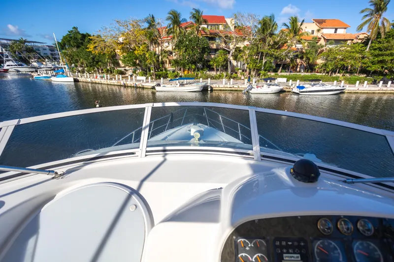 Slide: The Image of 2001 Cruisers Yachts 5000 Sedan Sport navigating a scenic waterfront with docked boats. - 44