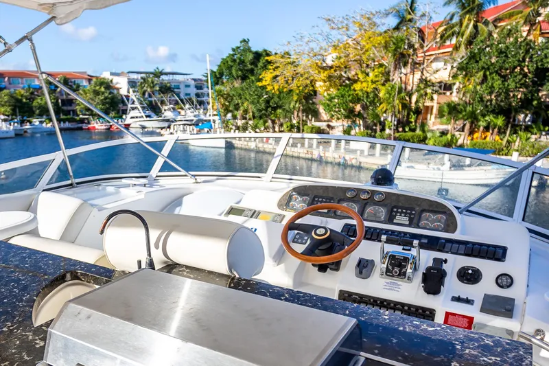 Slide: The Image of 2001 Cruisers Yachts 5000 Sedan Sport helm with marina view, featuring modern controls. - 47