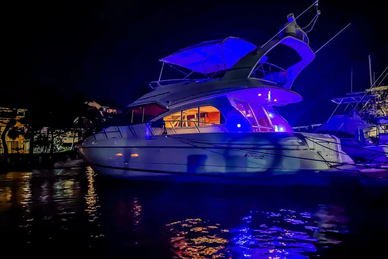 Slide: The Image of 2001 Cruisers Yachts 5000 Sedan Sport illuminated at night, docked with vibrant blue lights. - 73