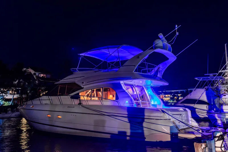 Slide: The Image of 2001 Cruisers Yachts 5000 Sedan Sport illuminated at night, docked with blue lights. - 78
