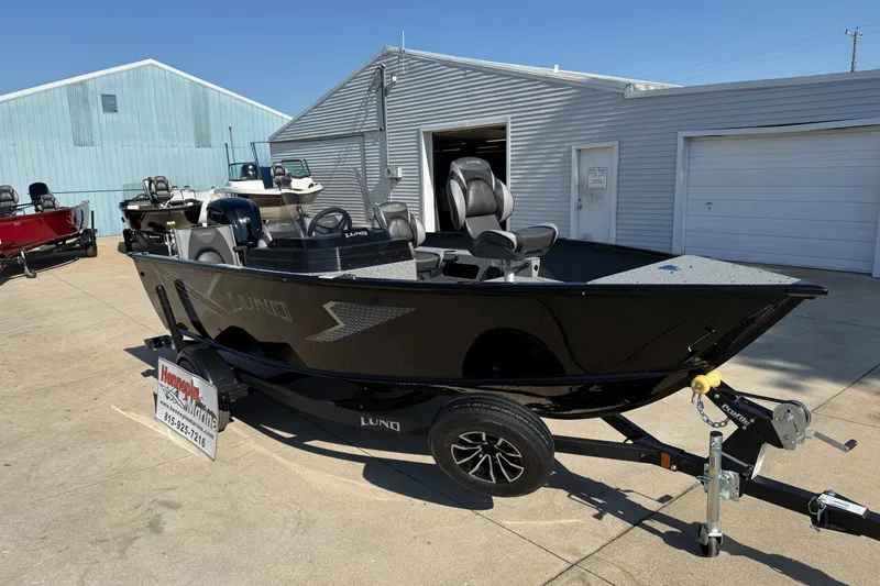 Slide: The Image of 2026 Lund 1675 Adventure SS boat on trailer outside a marine dealership. - 2