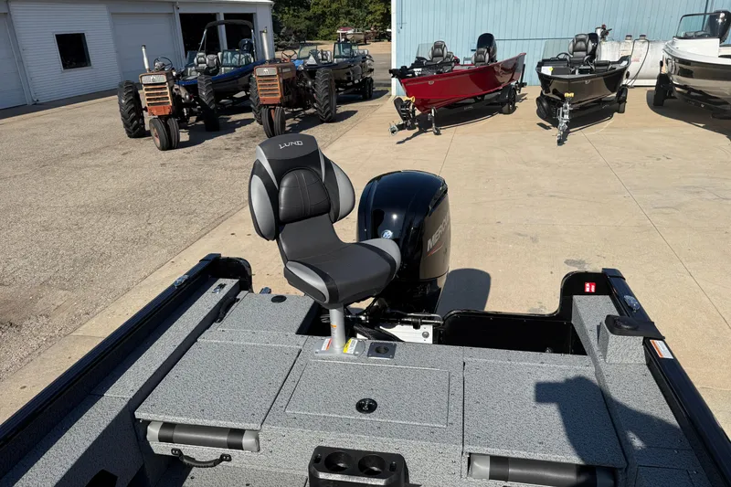 Slide: The Image of 2026 Lund 1675 Adventure SS boat with Mercury engine, parked near tractors and other boats. - 24