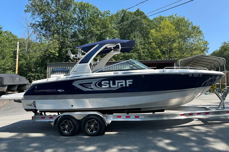 Slide: The Image of 2024 Chaparral 26 Surf boat on trailer, parked outdoors. - 2