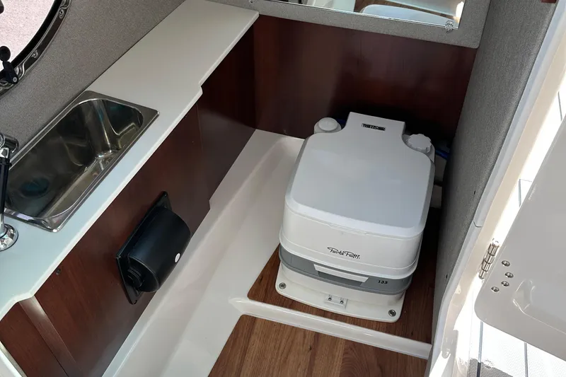 Slide: The Image of 2024 Chaparral 26 Surf boat interior with sink and portable toilet. - 8
