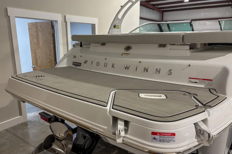 Slide: The Image of 2026 Four Winns H2 boat rear view in a showroom, showcasing swim platform and branding. - 4