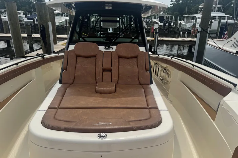 Slide: The Image of 2023 Scout 400 LXF boat with luxurious brown leather seating at a marina. - 25