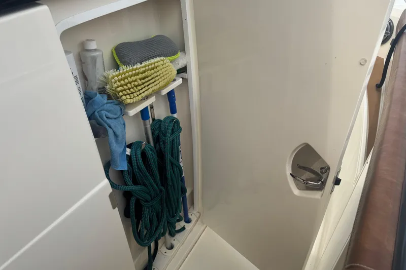 Slide: The Image of Storage compartment on 2023 Scout 400 LXF boat with cleaning supplies and ropes. - 27