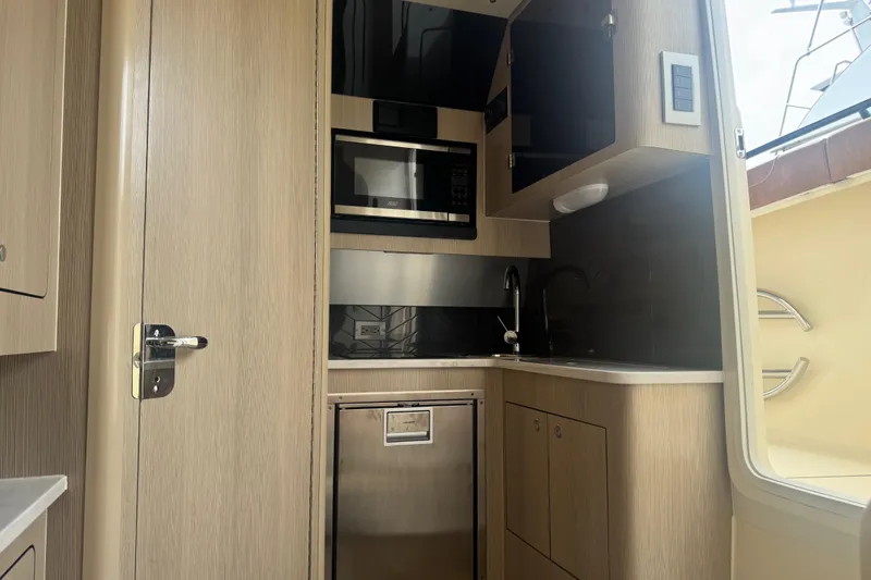 Slide: The Image of 2023 Scout 400 LXF boat interior kitchen with modern appliances and sleek wood finish. - 37