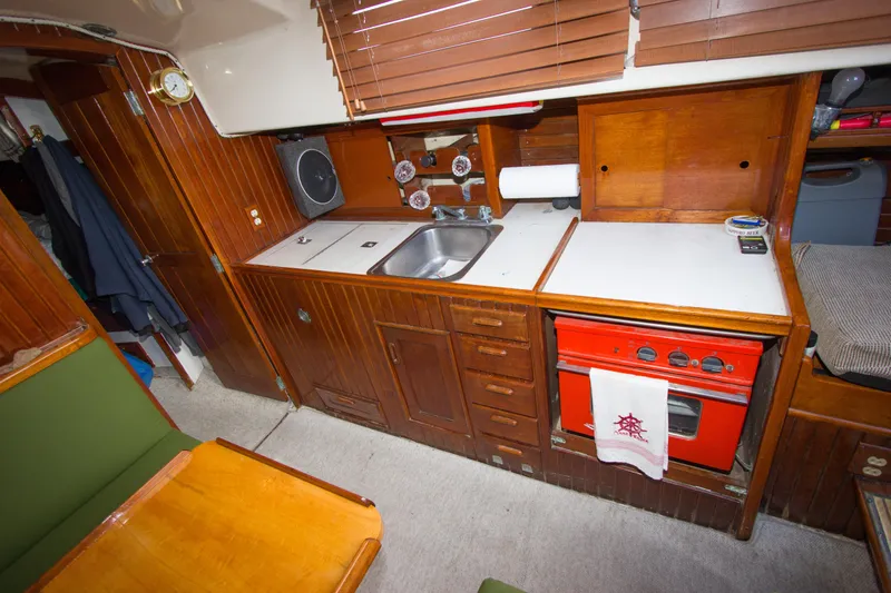 Slide: The Image of Vintage 1965 Pearson Vanguard yacht kitchen with wooden cabinetry and red stove. - 10