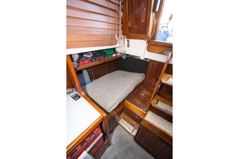 Slide: The Image of Interior of a 1965 Pearson Vanguard sailboat with wooden cabinetry and a cushioned berth. - 13