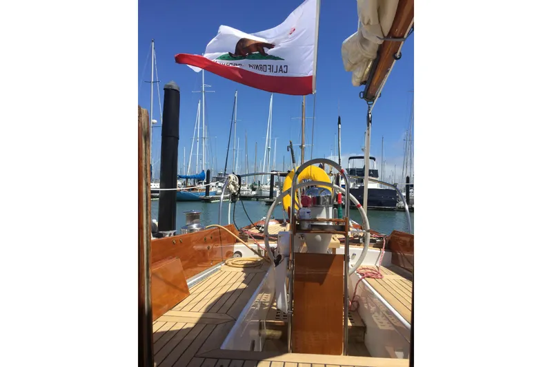 Slide: The Image of 1965 Pearson Vanguard sailboat docked, featuring a California flag and wooden deck. - 17