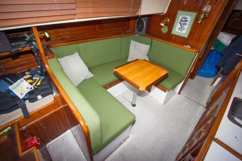 Slide: The Image of Cozy interior of a 1965 Pearson Vanguard sailboat with green seating and wooden table. - 8