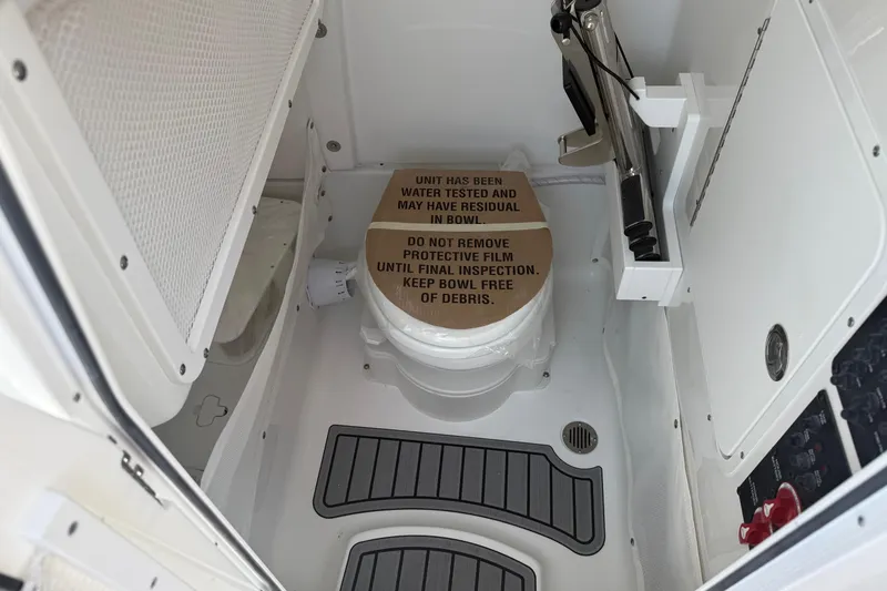 Slide: The Image of Interior of 2026 Sea Hunt Ultra 265 SE boat featuring a compact marine toilet. - 12