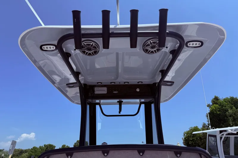 Slide: The Image of 2026 Sea Hunt Ultra 265 SE boat T-top with rod holders and speakers under clear sky. - 17