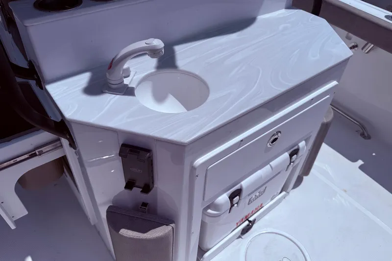 Slide: The Image of 2026 Sea Hunt Ultra 265 SE boat sink and storage area with cooler. - 2