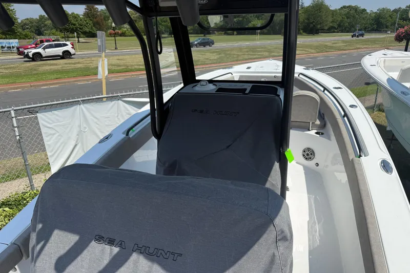 Slide: The Image of 2026 Sea Hunt Ultra 265 SE boat interior with covered seating, parked outdoors. - 8