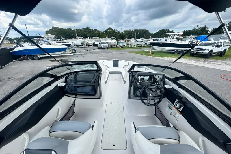 Slide: The Image of 2018 Scarab 195 G boat interior with steering wheel, seats, and dashboard, parked among other boats. - 13