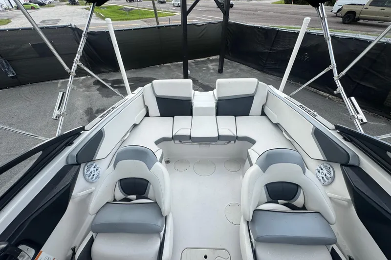 Slide: The Image of 2018 Scarab 195 G boat interior with white and gray seating, parked on pavement. - 18