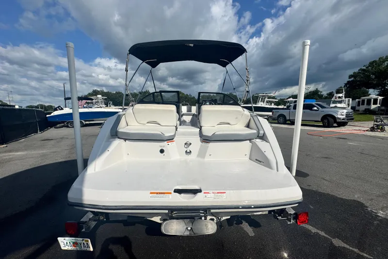 Slide: The Image of 2018 Scarab 195 G boat with canopy, parked on a trailer under a cloudy sky. - 8