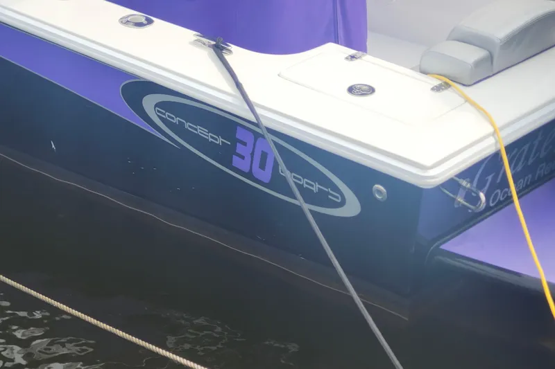 Slide: The Image of 2014 Concept 30 Cuddy boat with purple detailing docked on water. - 34