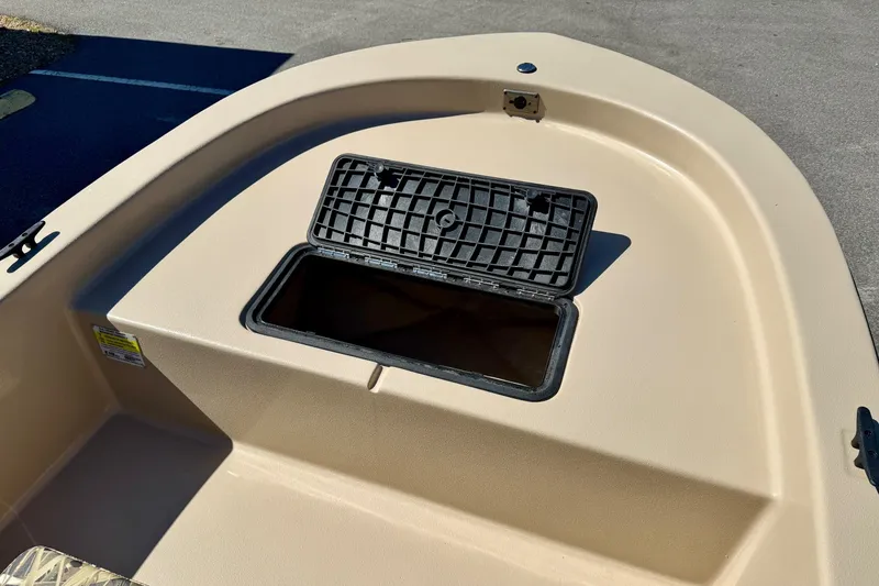 Slide: The Image of 2026 Carolina Skiff E18 JVX CC boat storage compartment, open lid, beige deck. - 11