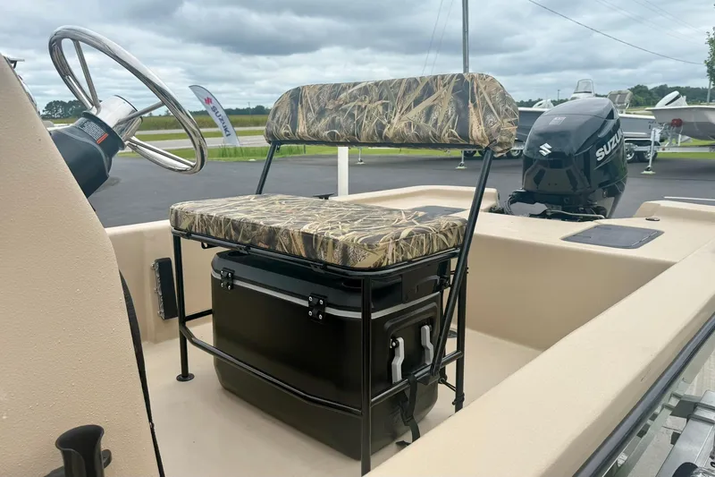 Slide: The Image of 2026 Carolina Skiff E18 JVX CC boat interior with camo seat and Suzuki outboard motor. - 18