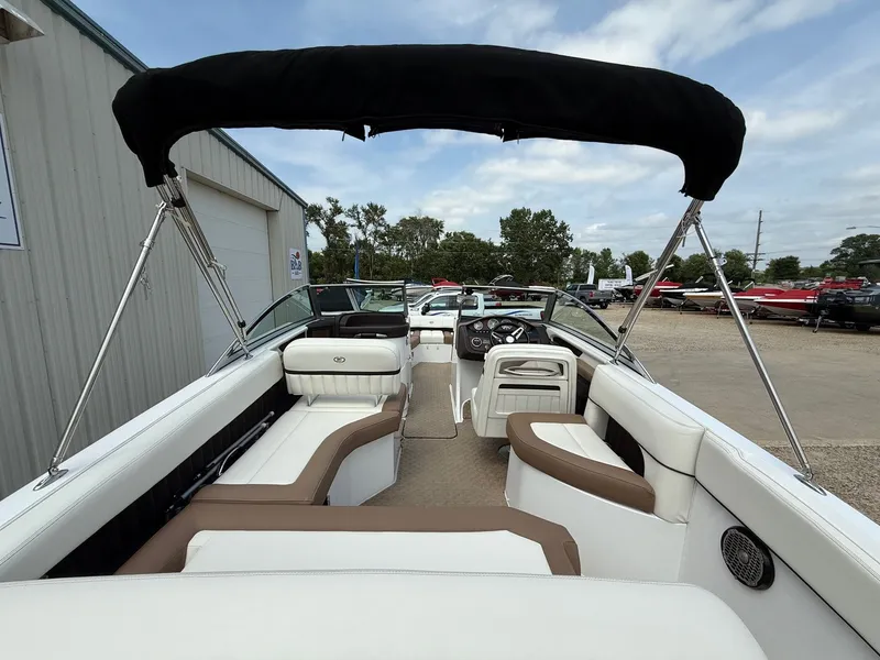 Slide: The Image of 2014 Cobalt 24SD boat interior with seating and steering wheel, parked outdoors. - 10
