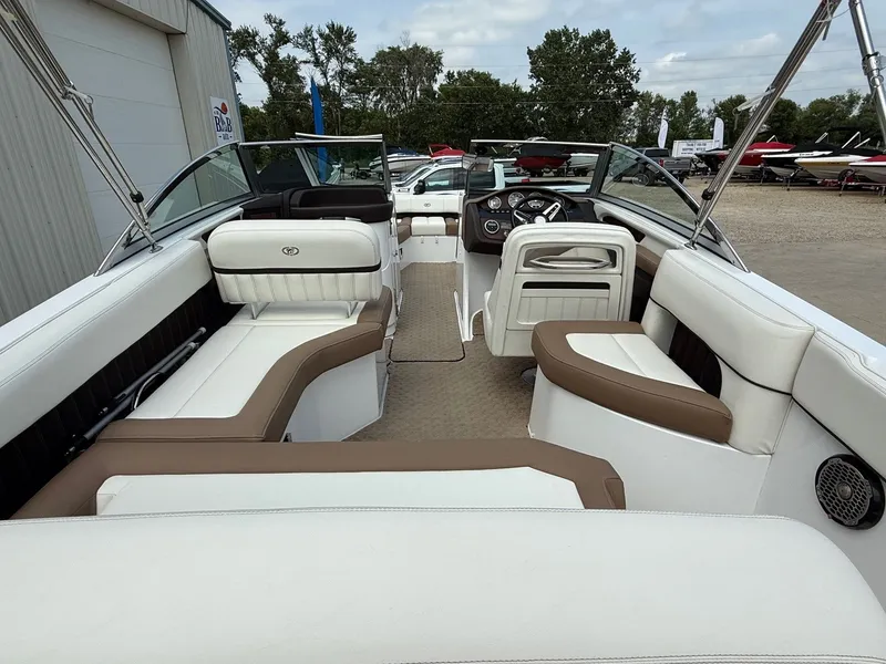 Slide: The Image of 2014 Cobalt 24SD boat interior with white and brown seating, parked outdoors. - 11