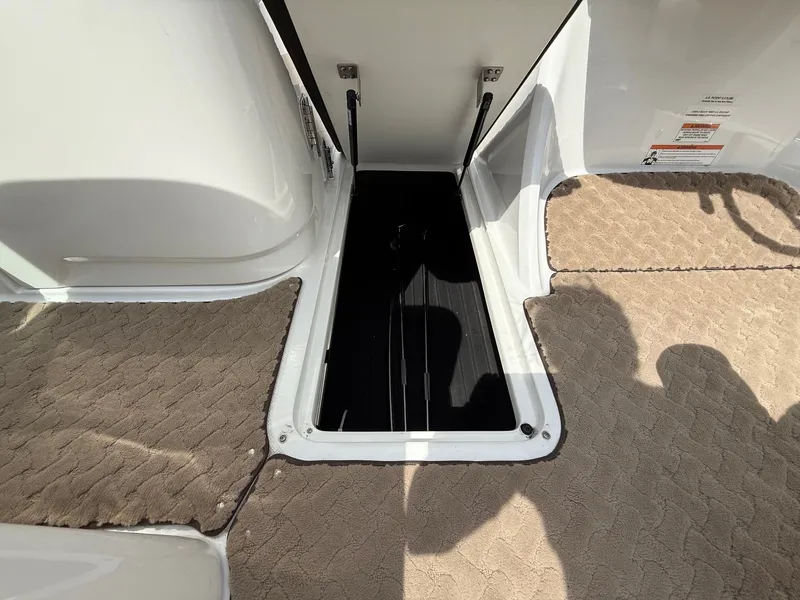 Slide: The Image of 2014 Cobalt 24SD boat storage compartment with beige carpet and open hatch. - 19