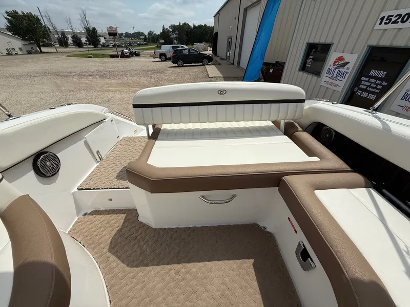 Slide: The Image of 2014 Cobalt 24SD boat interior with beige and white seating, parked near a building. - 27