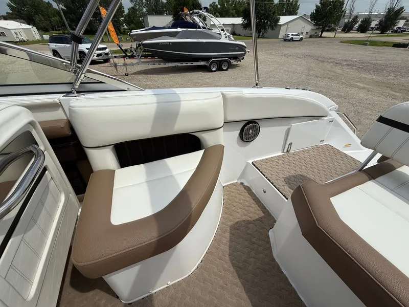 Slide: The Image of 2014 Cobalt 24SD boat interior with white and brown seating, parked on gravel. - 28