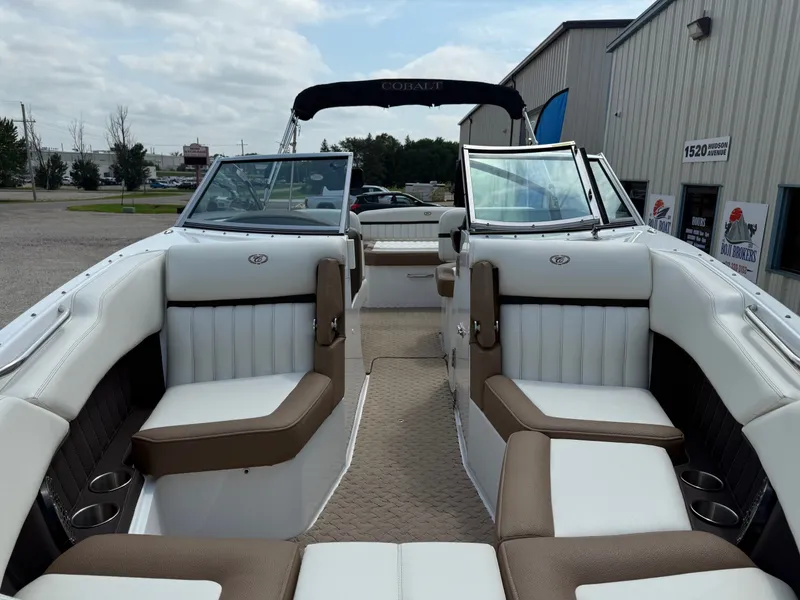 Slide: The Image of 2014 Cobalt 24SD boat interior with white and brown seating, docked near a building. - 4
