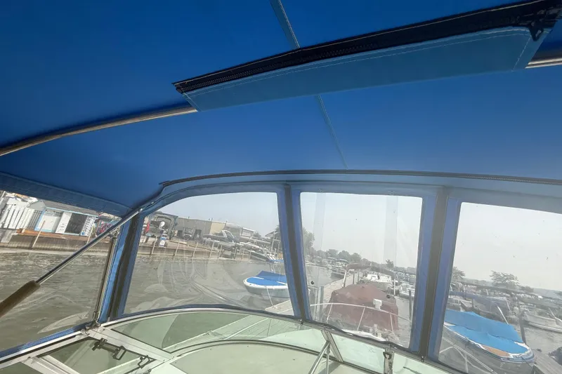 Slide: The Image of 2001 Cruisers Yachts 2870 Express interior view with blue canopy and marina background. - 12