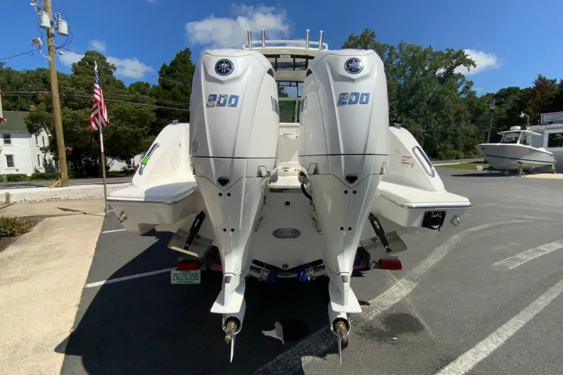 Slide: The Image of 2026 Pursuit DC 266 Dual Console boat with twin 200 horsepower engines, parked outdoors. - 10