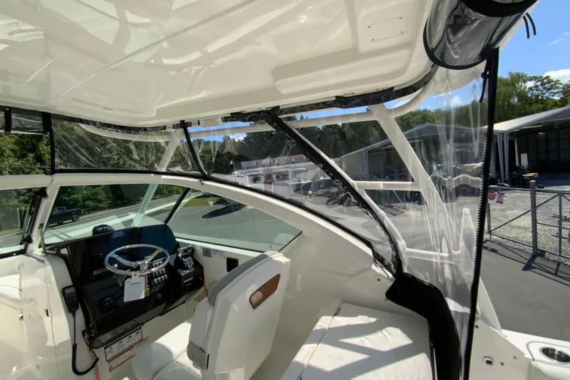 Slide: The Image of 2026 Pursuit DC 266 Dual Console boat interior with steering wheel and clear canopy. - 13