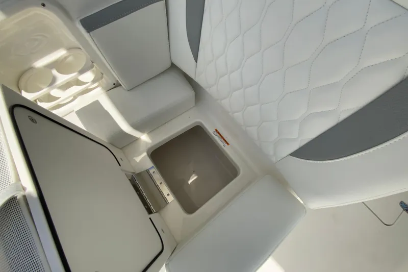 Slide: The Image of 2026 Pursuit DC 266 Dual Console interior with white quilted seating and storage compartment. - 19