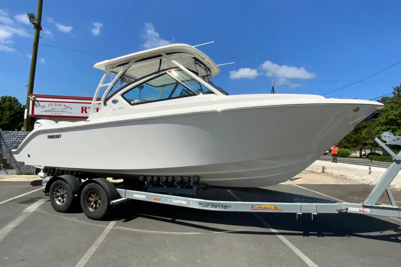 Slide: The Image of 2026 Pursuit DC 266 Dual Console boat on trailer under clear blue sky. - 3