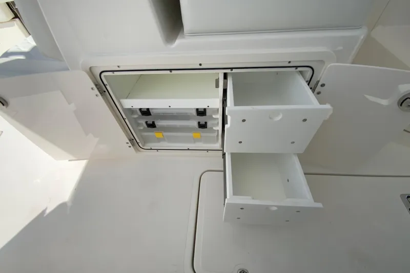 Slide: The Image of 2026 Pursuit DC 266 Dual Console boat storage compartments with open drawers. - 33