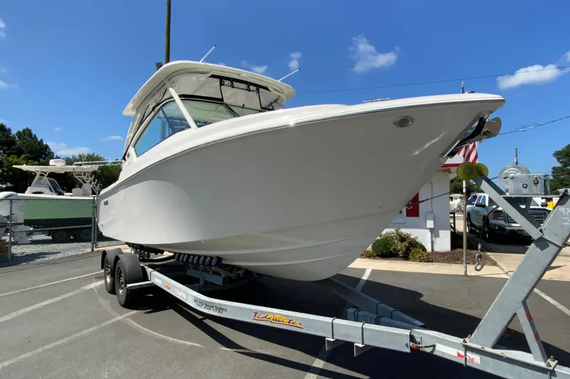 Slide: The Image of 2026 Pursuit DC 266 Dual Console boat on trailer, parked outdoors under clear blue sky. - 4