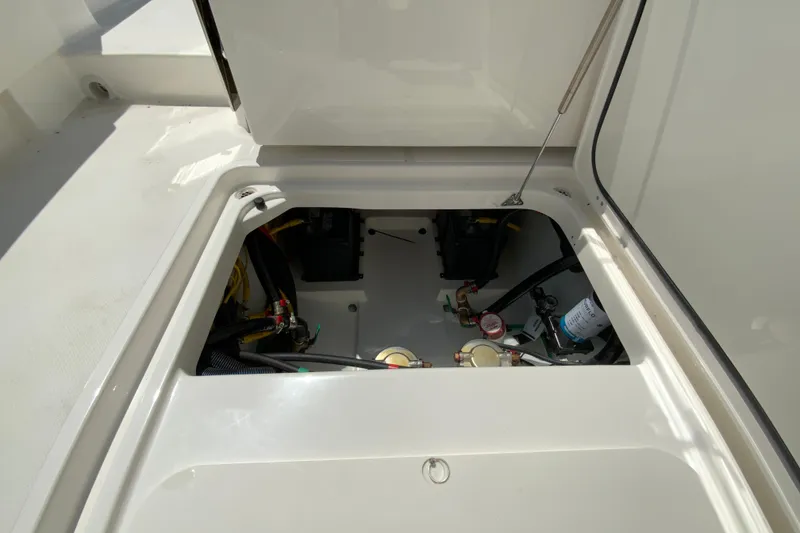 Slide: The Image of 2026 Pursuit DC 266 Dual Console boat storage compartment with visible wiring and components. - 42