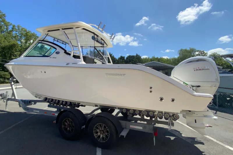 Slide: The Image of 2026 Pursuit DC 266 Dual Console boat on trailer under clear blue sky. - 8